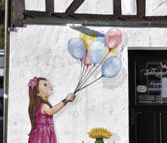 Wall painted with a child with balloons, in Adenau, © TI Hocheifel-Nürburgring_Jonathan_Andrews Wall painted with a child with balloons, in Adenau, © TI Hocheifel-Nürburgring_Jonathan_Andrews