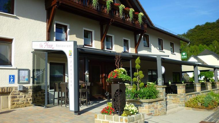 Ein charmantes Restaurant mit blühenden Pflanzen und einem einladenden Eingangsbereich. Die Fassade ist hell und freundlich, umgeben von einer gepflegten Landschaft.