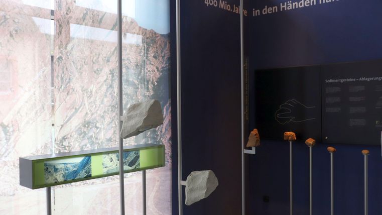 Ein Ausstellungsraum mit Informationen zu geologischen Formationen. Im Hintergrund sind Steine und textliche Erklärungen zu sehen.