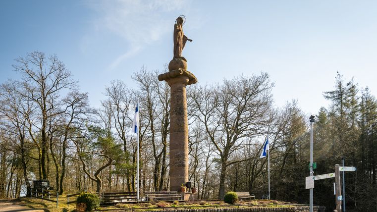 Mariensäule bei Waxweiler mit blauen Himmel und Bäumen im Hintergrund.