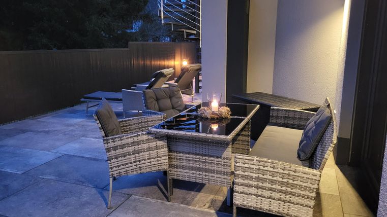 Ein gemütlicher Außenbereich mit modernen Möbeln und gedämpfter Beleuchtung. Die Atmosphäre ist entspannt und einladend.