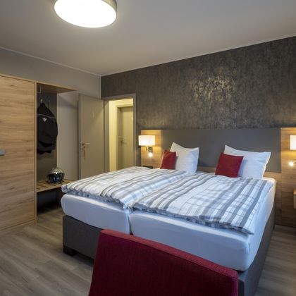 Ein gemütliches Hotelzimmer mit einem großen Bett und modernen Möbeln. Der Raum ist hell und gut ausgestattet, ideal für einen entspannenden Aufenthalt.