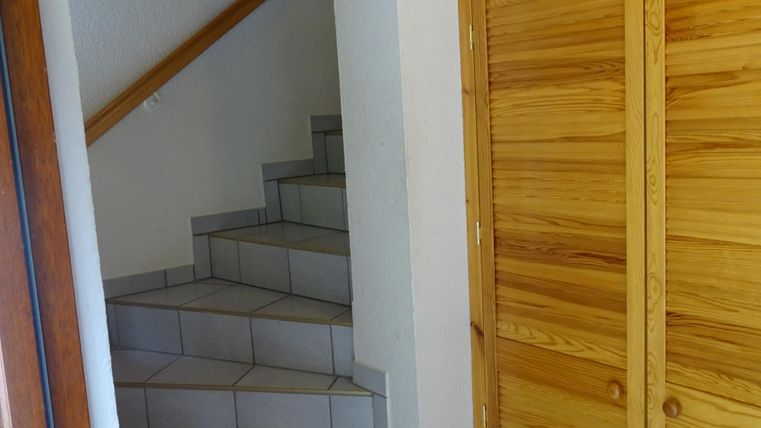 Ein heller Eingangsbereich mit einer Treppe, die zu einer oberen Etage führt. Rechts ist ein Holzschrank, der zusätzlichen Stauraum bietet.