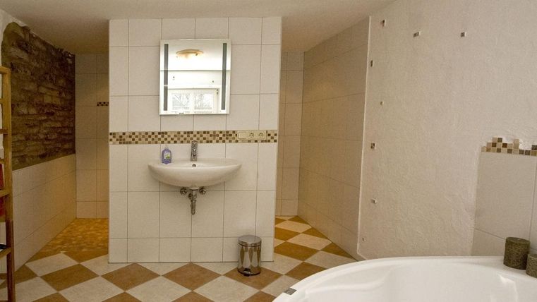 Ein modernes Badezimmer mit einer freistehenden Badewanne und einem Waschbecken. Der Boden ist in einem klassischen Schachbrettmuster gefliest.