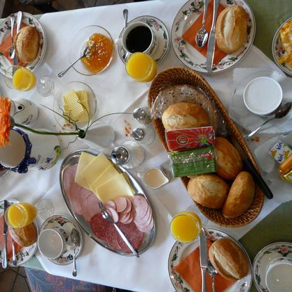Ein reichhaltiges Frühstücksbuffet mit Brötchen, Wurst, Käse und Eiern. Dazu gibt es Kaffee, Saft und verschiedene Marmeladen.