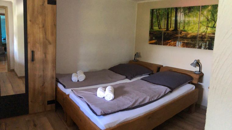 Une chambre confortable avec deux lits et un sol en poutres de bois. Sur le mur, il y a une image de la nature, et les lits sont décorés de serviettes fraîches.