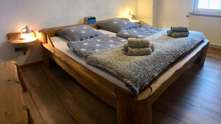 Une chambre confortable avec un grand lit en bois et des draps étoilés. Des serviettes sont posées sur le lit et il y a un éclairage doux.