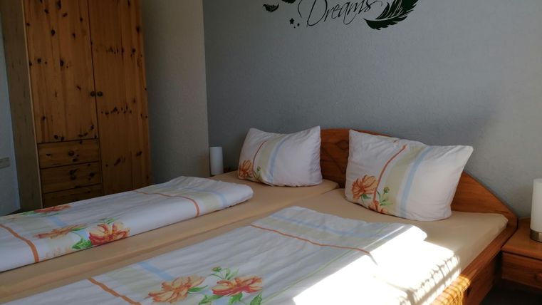 Une chambre confortable avec deux lits et une armoire en bois. Sur le mur se trouve l'inscription "Sweet Dreams".