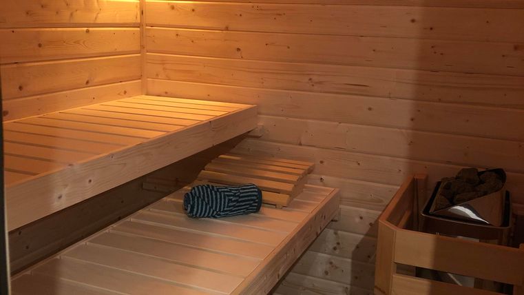 Une sauna confortable avec des bancs en bois et un éclairage doux. Un seau et une éponge sont prêts pour l'expérience de sauna.