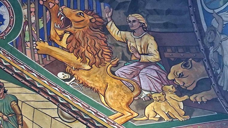 Eine farbenfrohe Wandmalerei zeigt einen Löwen, der brüllt, während ein Mensch vor ihm sitzt. Im Hintergrund sind weitere Löwen und Löwenjunge zu sehen.