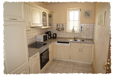 Eine moderne Küche mit hellen Schränken und einer Arbeitsplatte aus Marmor. Sie ist gut ausgestattet mit einem Herd, einer Mikrowelle und einem Spülbecken.