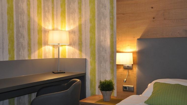 Ein modernes Zimmer mit einer Holzwand und grünen Akzentstreifen. Der Raum ist hell erleuchtet mit einer gemütlichen Atmosphäre.