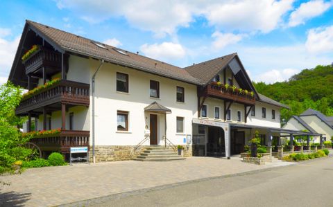 Ein modernes Gebäude mit eleganten Balkonen und einem einladenden Eingang. Umgeben von einem ruhigen, grünen Landschaftsbild.