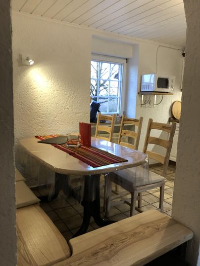 Un espace repas confortable avec une grande table et des chaises. La fenêtre offre une vue sur l'extérieur et la pièce est bien éclairée.