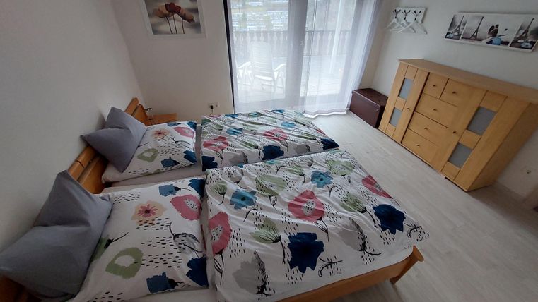 A cozy bedroom with two single beds and colorful bedspreads. Large windows let in plenty of daylight, making the room bright and welcoming.