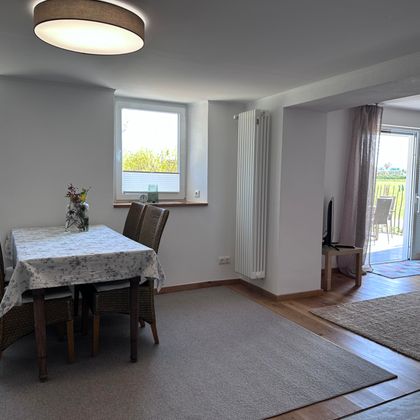 A bright and inviting dining room with a table and chairs. Large windows let in plenty of daylight and provide a view outside.