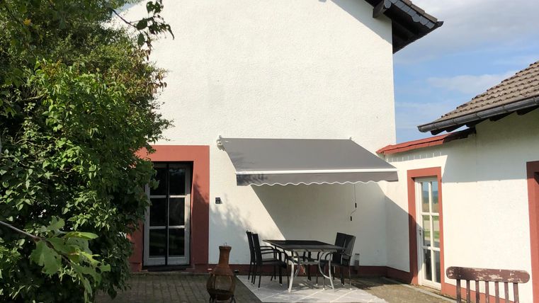 Une maison bien conçue avec un jardin et une terrasse. L'extérieur est bien entretenu et offre des places assises.