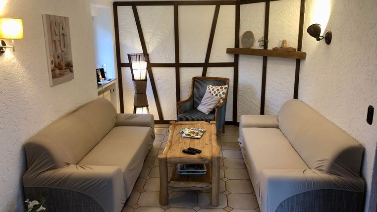 Un salon confortable avec deux canapés et une table en bois.
Sur le mur, il y a des éléments décoratifs et des lampes.