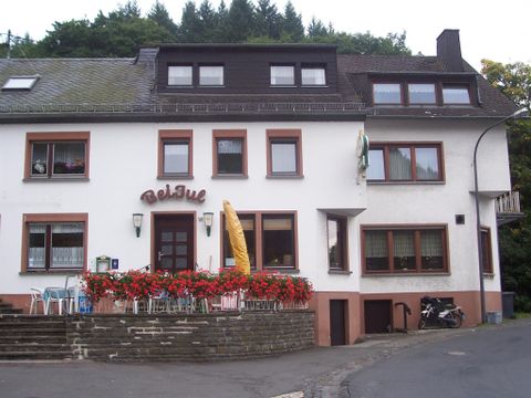 Ein rustikales Gasthaus mit einem einladenden Eingang. Vor dem Gebäude steht ein bunter Blumenschmuck.