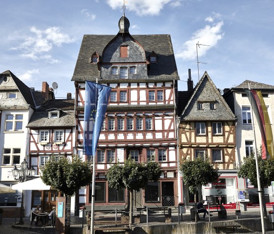 Fachwerkhäuser im historischen Stadtkern von Adenau, geschmückt mit Europaflagge und Deutschlandflagge. Menschen sitzen draußen unter Sonnenschirmen., © TI Hocheifel-Nürburgring,Jonathan_Andrews