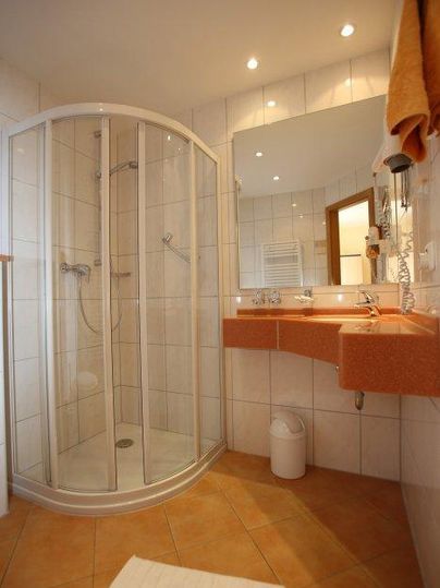 Een moderne badkamer met een ronde douche en een wastafel. De muren zijn licht betegeld en de verlichting is aangenaam.