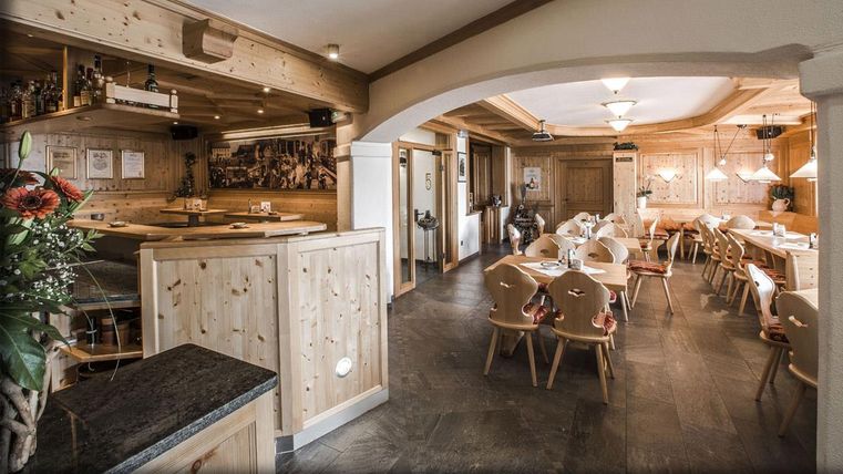 Ein gemütliches Restaurant mit Holzmöbeln und warmem Licht. Die Tische sind für Gäste vorbereitet und vermitteln eine einladende Atmosphäre.